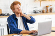 © kucherav - Overworked young male massaging neck feeling hurt pain from sedentary job. Tired stressed freelancer man suffering from neckpain working in the home office sitting at table