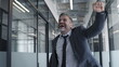 © Synthex - Happy businessman jumping with yes gesture in office, celebrating success, close-up