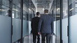 © Synthex - Two serious men with briefcase walking along office hall, business meeting, back view