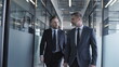© Synthex - Two serious businessmen walking in office, discussing project tasks, planning business strategy