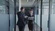 © Synthex - Male boss giving work instructions to female secretary while walking in office corridor