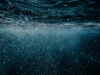 Tropical blue ocean with white bubbles underwater in Mediterranean Sea. Ocean background, underwater blue ocean background with sandy sea bottom, Blue deep water abstract natural bubble background.