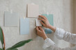 Woman hanging blank paper mock ups on wall. Design paints, reference templates for inspiration.Creating a project. Architectural or design bureau.