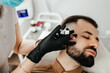 © Максим Галінский - Beauty treatments for a stylish young man with a beard. Beautician makes beauty injections in a man's face