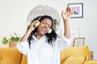 © CarlosBarquero - Motivated young Latin woman listening to music with headphones while sitting on sofa at home.
