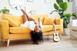 © CarlosBarquero - Young African American woman sings motivated on the sofa at home. Girl with headphones listening to music in living room. Indoor lifestyle