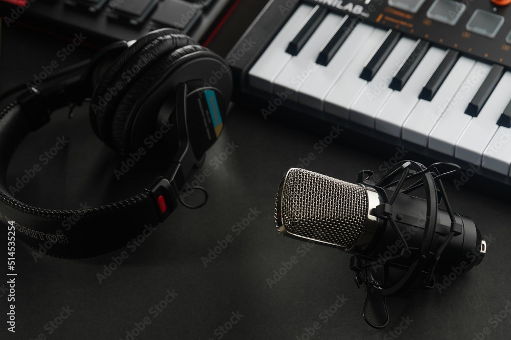 Midi keyboard, studio microphone and studio headphones on a dark gray ...
