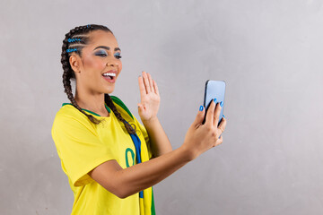 Brazilian fan woman cheering for brazil at world cup 2022 on video call talking to friends remotely, cellphone, holding cellphone, communication, technology