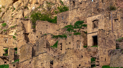 Wall Mural - ruins of stone houses attached to the rock in the depopulated village of Gamsutl in the sunset rays