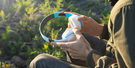 Wall Mural - Caucasian man holding headphones at outdoor.