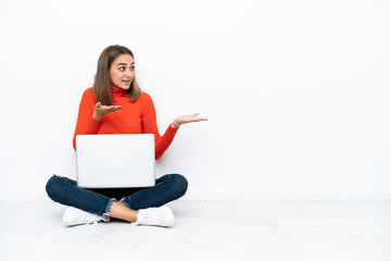 Wall Mural - Young caucasian woman sitting on the floor with a laptop with surprise facial expression