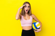 Young woman playing volleyball isolated on yellow background with surprise expression