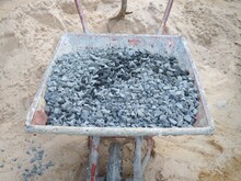 Worker Scoop Stones Into Wheelbarrows. To Transport Stones To The Mortar Mixing Point To Build Wall.