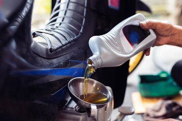 Mechanic is replacing a new bottle of lubricant for a motorcycle.