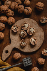 Sticker - Open dried walnuts with nut opener on a wooden board. Walnut peeling process. Organic food with natural protein.