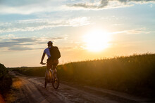 Cyclist Riding A Bike At Sunset. Concept Of Extreme Cycling. Man Driving Bicycle On The Way To The Field In The Summer.