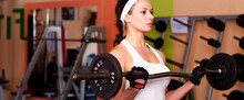 Young Woman Lifting Weights In The Sports Gym