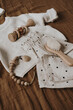 © Floral Deco - Clothes and accessories for newborn baby. Sweater, joggers, brush, pacifier holder clip on brown muslin linens. Aesthetic luxury baby fashion store, shopping concept