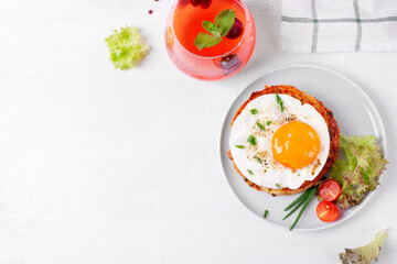 Fried egg on the stack of zucchini fritters and berry lemonade in the glass on white table. Top view. Mockup with copy space 