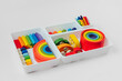 Colorful wooden toys in the colors of the rainbow in plastic box.  Concept of organizing and storing children's toys. Cute kids toys to play and for decorating children's room.