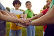 © Studio Romantic - Bunch of children playing together on a good summer day. Group of happy friends standing in a circle in a green park or field, smiling and stacking their hands. Cropped closeup shot. Teamwork concept