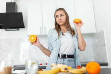 Cheerful young woman having fun with orange slices in the kitchen. Healthy food. Energy Boost, Vitamin C