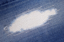 Blue jeans denim background texture. Torn jeans fabric material surface