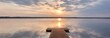 Busnieku lake at sunset. Ventspils, Latvia. Wooden pier. Soft sunlight, glowing clouds, symmetry reflections in a crystal clear water. Spring, early summer. Panoramic view. Nature, ecology, ecotourism