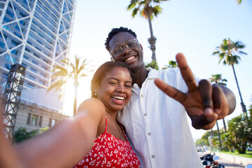 Selfie of a young black couple looking at camera smiling. Concept of vacation and relationship. African American couple having fun enjoying holidays