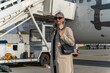 © Friends Stock - Woman passenger in sunglasses standing outdoors at airport near plane during boarding