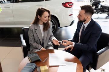 Wall Mural - car dealership employee handing the keys to a new car to a young woman