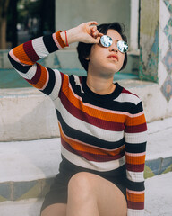 Cheerful young woman in a long sleeved striped shirt and black skirt in a white and blue background