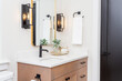 A modern farmhouse bathroom with wood cabinets,quartz countertops and black pulls.