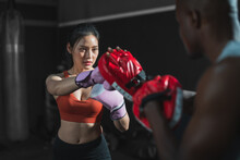 Asian Fit Female Boxing Training With Her Trainer At Gym.Sportwoman  Wearing Boxing Gloves Exercise And Punch To Pads For Boxing