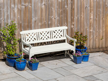 White Painted Garden Outside Seating Bench With Colourful Potted Plants Flowers