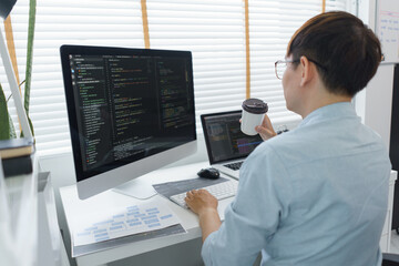 Wall Mural - software development concept, male programmer checking website programming and drinking coffee