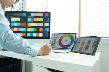Wall Mural - creativity concept, male graphic designer choosing color swatch samples on document and designing