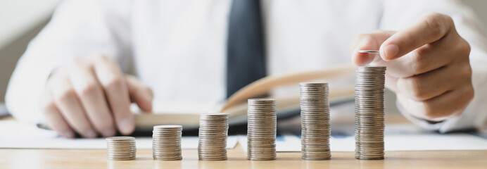 Man's hands put the coins arranged in steps, Managing your finances or saving money for future use, Saving for investment, Saving money for business growth or long-term profitability.