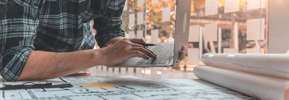 Young man with a laptop plotting a system of building structures in ...
