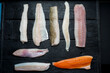fillets of fresh different fish cut out lie on a black background