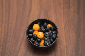 Wall Mural - Blueberries with physalis in a bowl on wood table