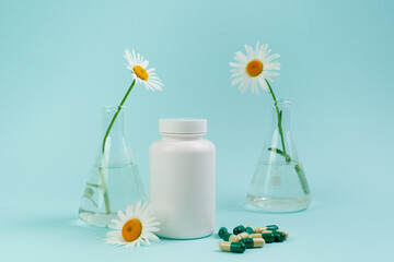 Wall Mural - A bottle of pills on a blue background. Flasks with medicinal plants. Place for text. Medical concept photo. Chamomile and pills