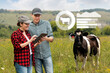 © scharfsinn86 - Farmers with tablet computer inspects cows in the pasture. Herd management concept.