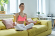 © gstockstudio - Attractive young woman in sports clothing meditating on the couch at home