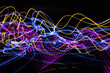 Long exposure light painting photograph of neon colour fairy lights in an abstract swirl pattern against a black background