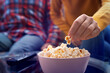 Caucasian couple sitting on sofa with popcorn and tv remote