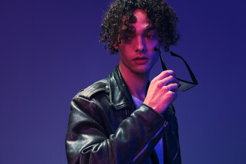 Cyberpunk style curly man leather jacket mirror eyewear looks aside posing isolated on color pink blue studio background. Cool fashion offer. Huge Seasonal Sale New Collection concept. Copy space ad