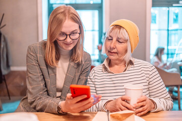 Two young caucasian women enjoy social media on their smart phones during their lunch break at their company court yard, modern office building in the background, good for modern lifestyle. 