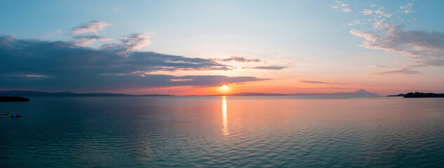 Sunset over calm ocean panorama. Orange and blue color sunrise seascape, Aegean Sea, Greece.