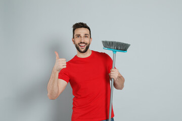 Wall Mural - Handsome man with broom on grey background